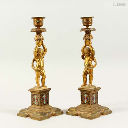 A PAIR OF 19TH CENTURY FRENCH CUPID CANDLESTICKS on enamel coloured columns. 10.5ins high.