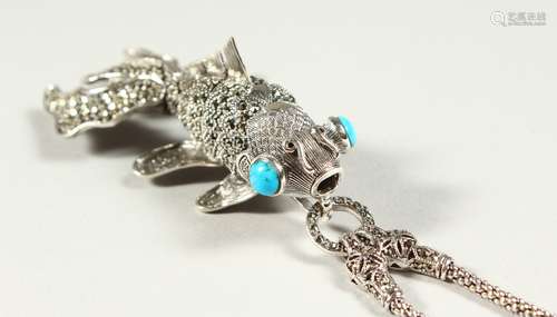 A LARGE SILVER ARTICULATED TURQUOISE EYE FISH PENDANT on a chain.