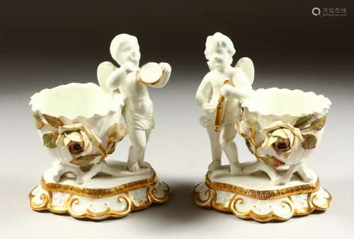 A PAIR OF MOORES TYPE WHITE GLAZED CUPIDS WITH BASKETS encrusted with flowers, on gilt scroll bases.