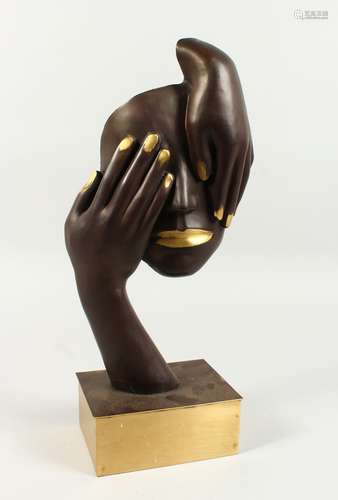 AN ABSTRACT BRONZE OF A FACE AND TWO HANDS. 1ft 6ins high.