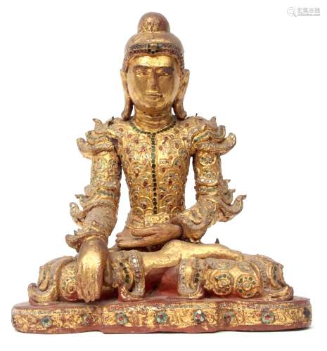 Wooden carving of a Buddha in typical pose, the wood with painted gilt decoration and inlaid glass
