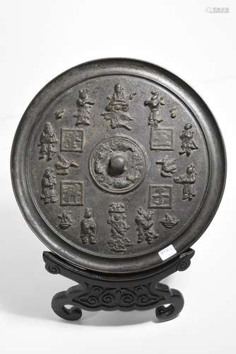 Miroir en bronze sculpté et patiné, Chine, époque Ming, sur un socle en bois sculpté (petits accidents au socle ) (Ø 26cm)