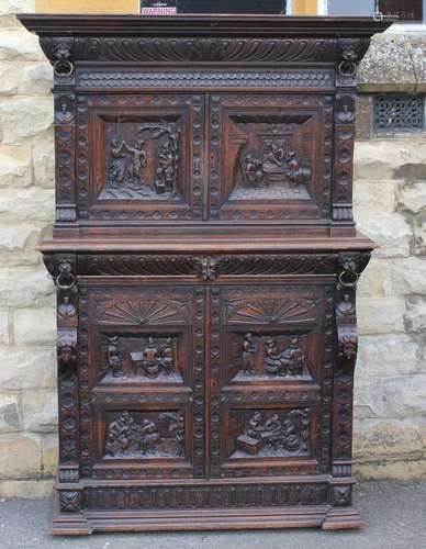 A Heavy Jacobean-Style Oak Court Cupboard; the cupboard having two splendidly carved cupboard doors above, with four interior drawers, two carved doors open to reveal a single shelf, the cupboard is decorated with carved figures and lion heads with rings, approx 123 x 48 x 167 cms