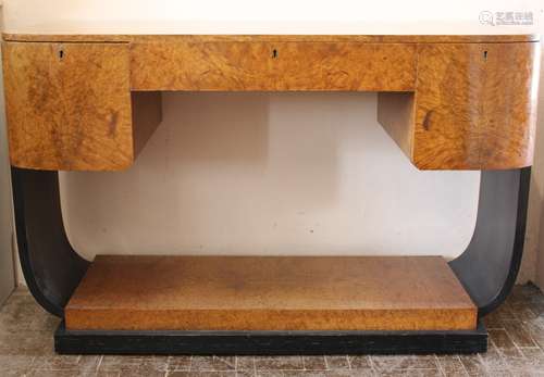 An Art Deco Walnut Writing Desk, a central draw flanked by two short drawers, raised on an ebonised plinth and supports approx 115 w x 15 d x 77 cms h