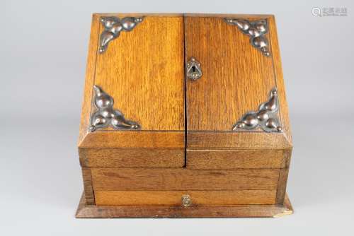 An Edwardian Oak Writing Slope; the slope with copper decorative corner pieces, double doors opening to fitted interior with glass ink bottle, drawer beneath, approx 30 x 19 x 26 cms