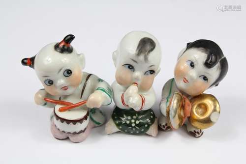 Three Chinese Porcelain Figurines, modelled as toddlers playing instruments