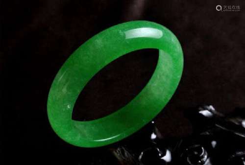 A NATURAL GREEN JADE BANGLE.