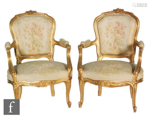 A pair of early 20th Century French fauteuil style open armchairs, the giltwood frames carved with