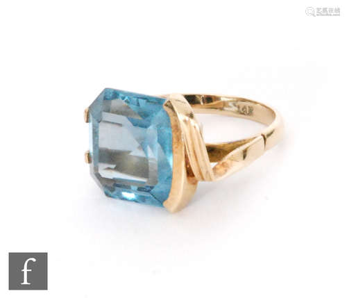 A 14ct single stone blue topaz ring, claw and part collar set square stone to a split head, weight