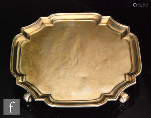 A hallmarked silver canted square small salver of plain from raised on four scroll feet, length