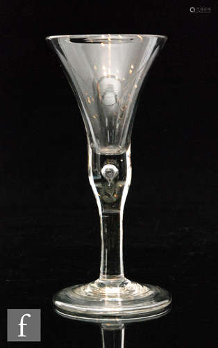 An 18th Century drinking glass with a flared trumpet bowl above a plain teared stem and folded