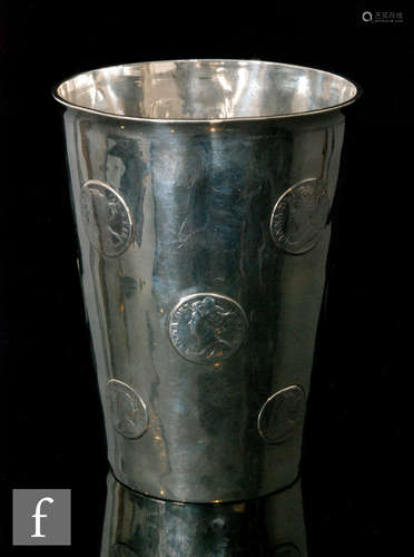 A hallmarked silver large beaker with twelve inset Queen Anne shillings and a half crown to base,