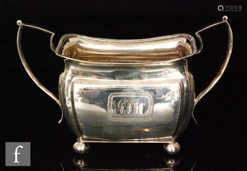 An Irish silver boat shaped, twin handled sugar basin raised on four ball feet below part bright cut