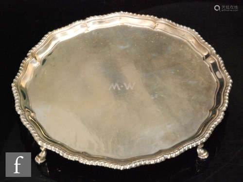 A hallmarked silver circular salver with gadroon border and raised on three stepped pad feet,