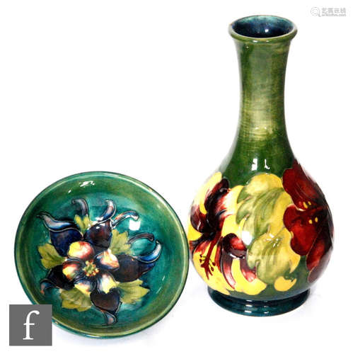 A Moorcroft Pottery vase of footed bottle form decorated in the Hibiscus pattern against a green