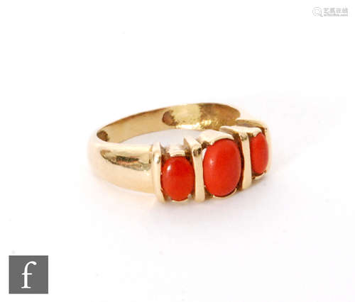 An 18ct three stone coral ring , oval channel set stones to a plain shank, weight 5.2g, ring size R.