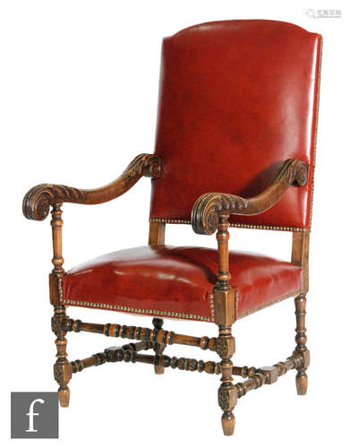 An early 20th Century Wainscot style armchair, the beech frame carved with acanthus armrests and