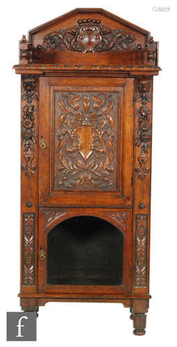 A Victorian carved oak floorstanding cabinet enclosed by an a carved acanthus panelled door below