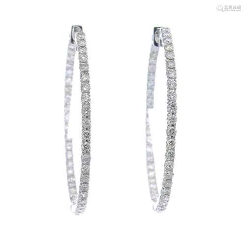 A pair of diamond hoop earrings.Estimated total diamond