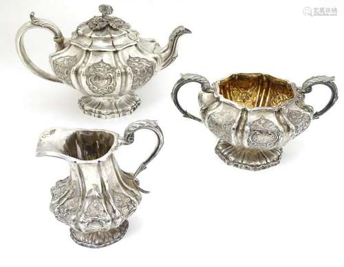 A silver three piece tea set decorated with floral