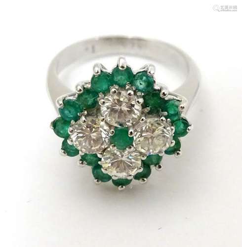 An 18ct white gold ring set with diamonds and emeralds