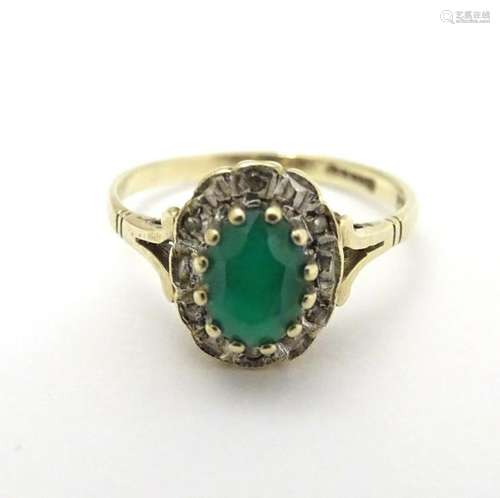 A 9ct gold ring set with emerald bordered by diamonds.