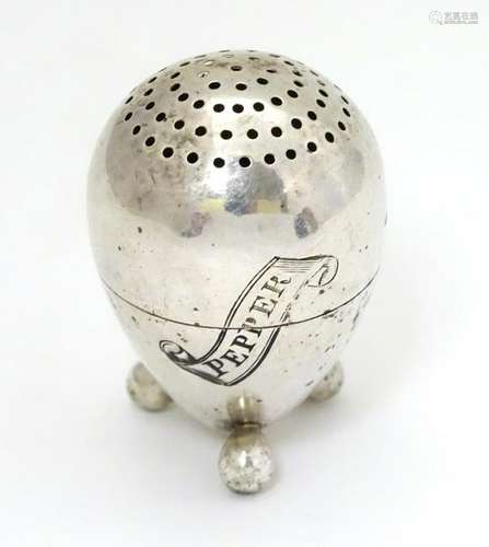 A Sterling silver pepperette of egg form on three feet.