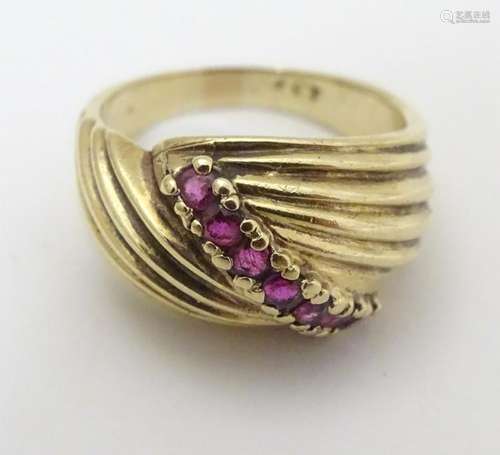 A 9ct gold ring set with 7 rubies in a linear setting.