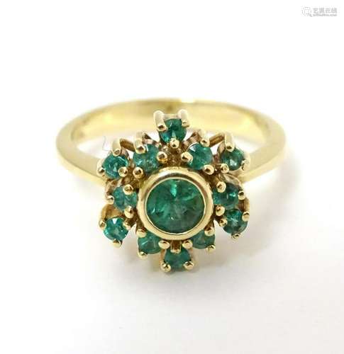 An 18ct gold ring set with emerald. The central emerald