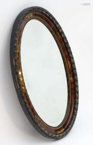 An early 20thC oval mirror with carved wooden