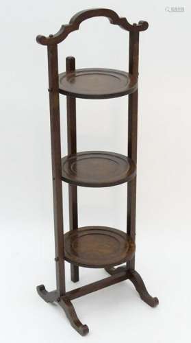 An early 20thC oak folding cake stand, with a shaped