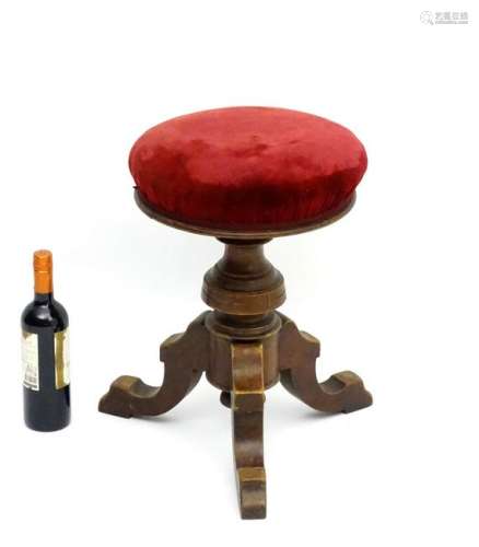 A Victorian walnut adjustable stool, having a turned